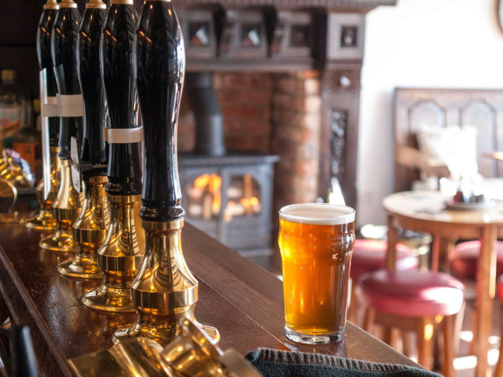 a pint of beer on a bar with seating in the background